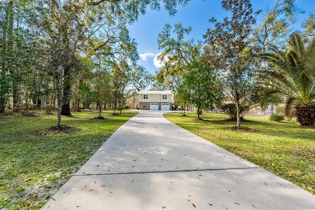 A long concrete driveway leads to a two-story house with a two-car garage — 498 SW MANATEE TERRACE, FORT WHITE, FL
