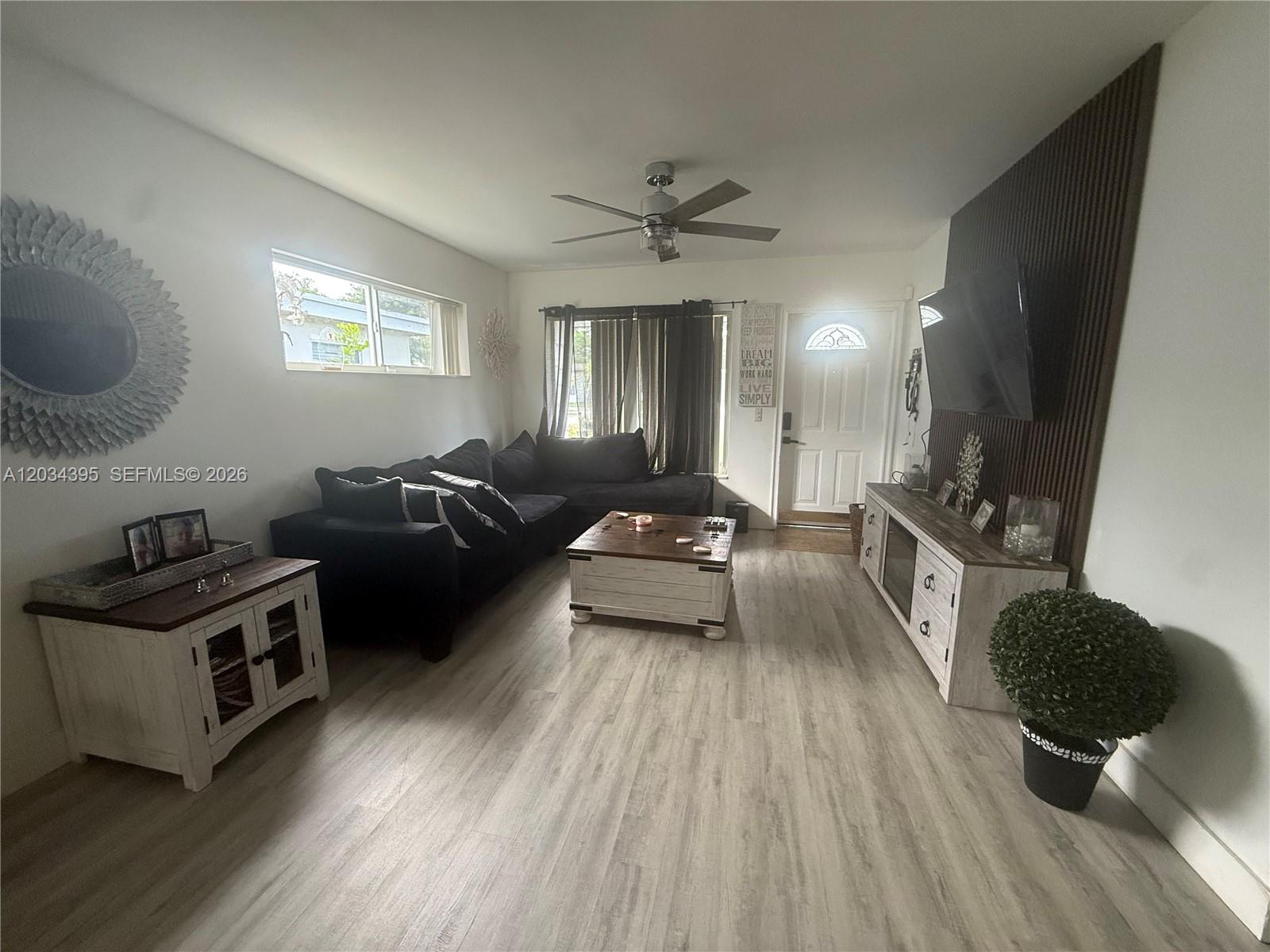 A living room features a dark sectional sofa, a wood-topped coffee table, and a wall-mounted television — 2538 Coolidge St, Hollywood FL 33020, HOLLYWOOD, FL