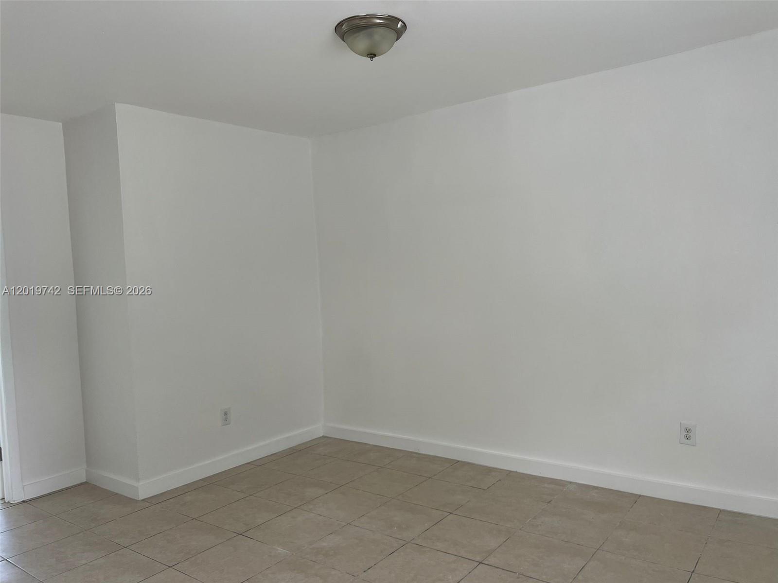 An empty room with white walls, beige tile flooring, and a ceiling light fixture — 4245 NW 24th Ave # 1, Miami FL 33142, MIAMI, FL