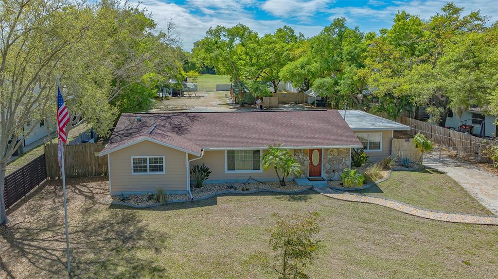 An aerial view of a single-story house with tan siding, a stone facade, and a flagpole — 3818 GOCIO ROAD, SARASOTA, FL
