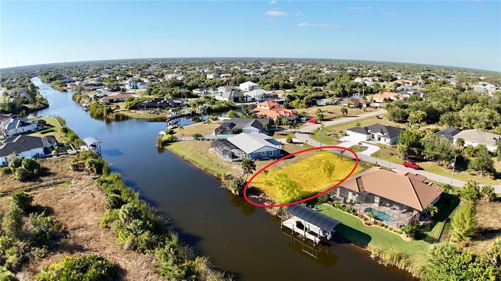 An aerial view shows a vacant waterfront lot highlighted by a red oval — 9580 PRESIDENT CIRCLE, PORT CHARLOTTE, FL