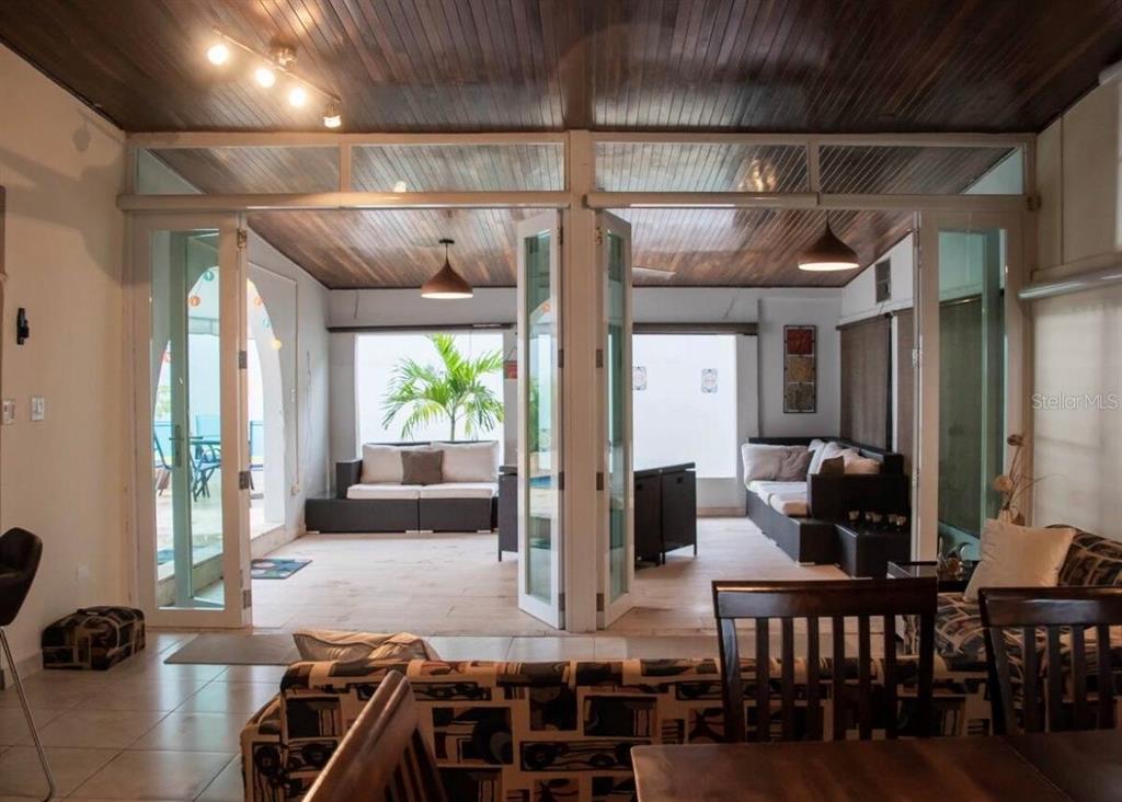 A living room opens through glass doors to a covered patio with a wood ceiling — 14 PALMA DE SIERRA, CAROLINA, PR