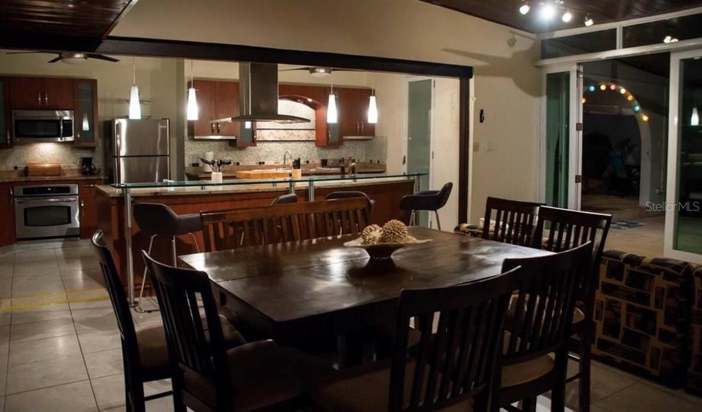 A dining area with a wooden table and chairs sits in front of an open kitchen — 14 PALMA DE SIERRA, CAROLINA, PR