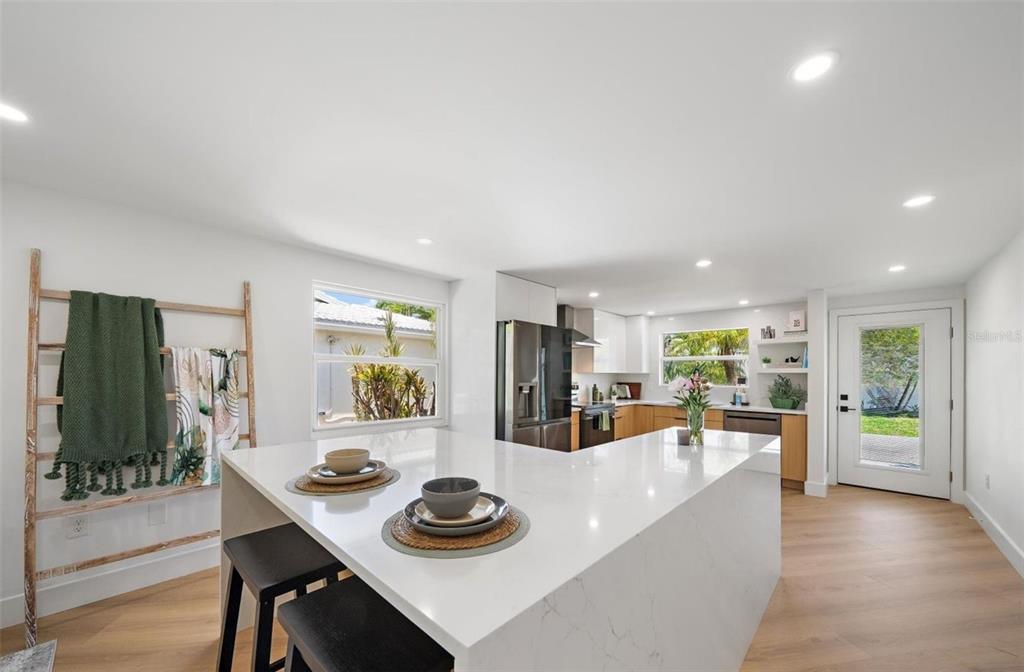 A modern kitchen features a large white quartz island, light wood flooring, and stainless appliances — 578 SPANISH DRIVE S, LONGBOAT KEY, FL
