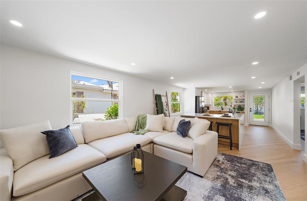 A bright living room features a white sectional sofa, dark coffee table, and open kitchen — 578 SPANISH DRIVE S, LONGBOAT KEY, FL