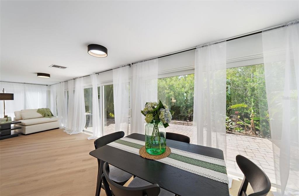 A dining area with a dark table and chairs overlooks a patio through sliding glass doors — 578 SPANISH DRIVE S, LONGBOAT KEY, FL