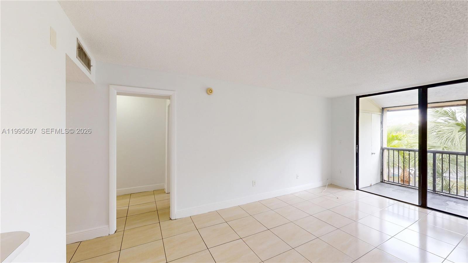 A bright, tiled living area features a doorway to another room and a sliding glass door — 14201 N Kendall Dr # 401D, Miami FL 33186, MIAMI, FL