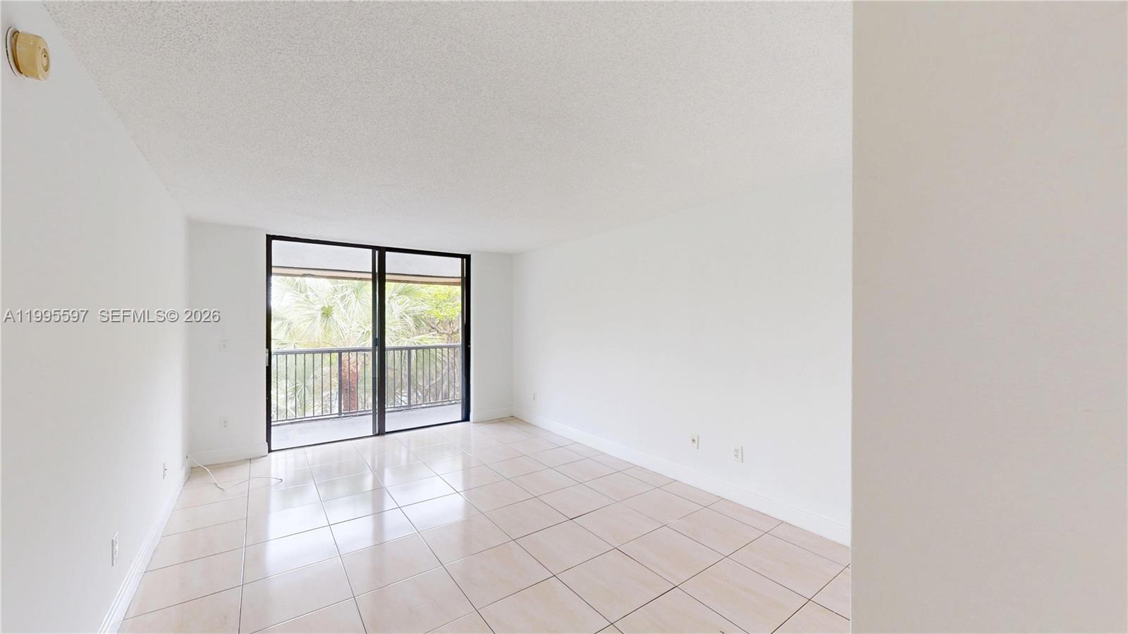 An empty room with white walls, tiled floors, and a sliding glass door to a balcony — 14201 N Kendall Dr # 401D, Miami FL 33186, MIAMI, FL