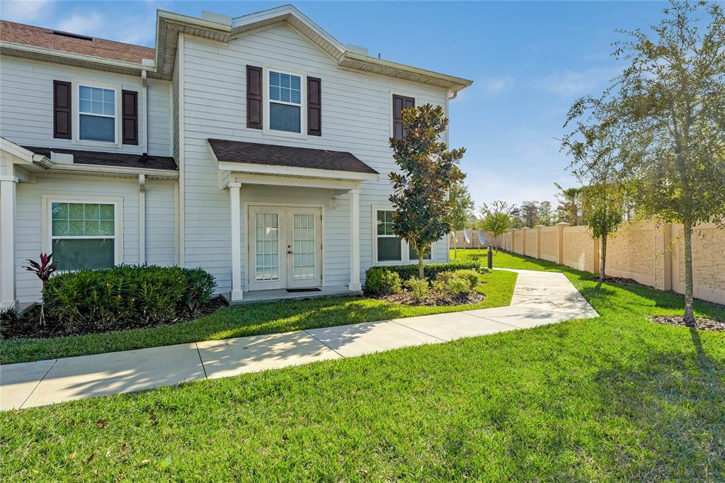 A two-story light-colored siding townhouse with a front walkway and a small landscaped yard — 3212 CUPID PLACE, KISSIMMEE, FL