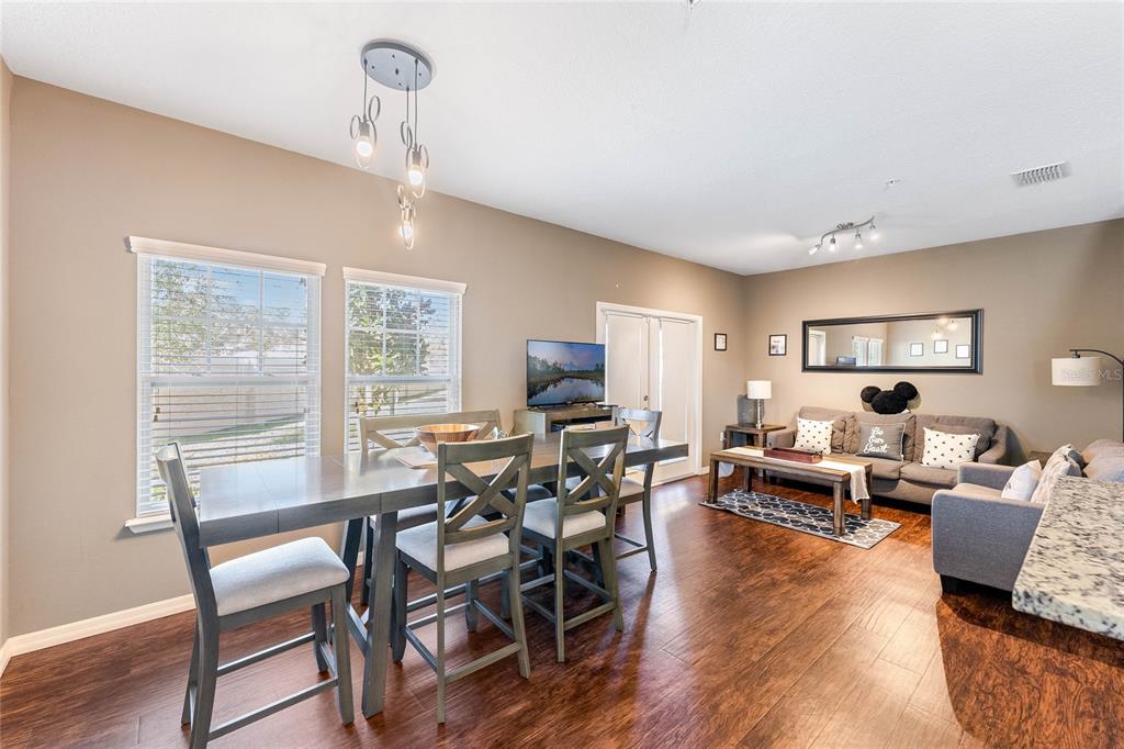An open-concept living and dining area with dark wood floors and neutral walls — 3212 CUPID PLACE, KISSIMMEE, FL