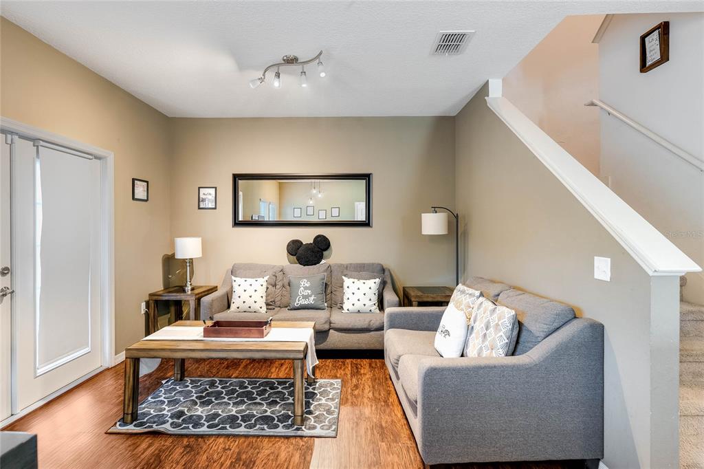 A living room features two gray sofas, a coffee table, and a staircase — 3212 CUPID PLACE, KISSIMMEE, FL