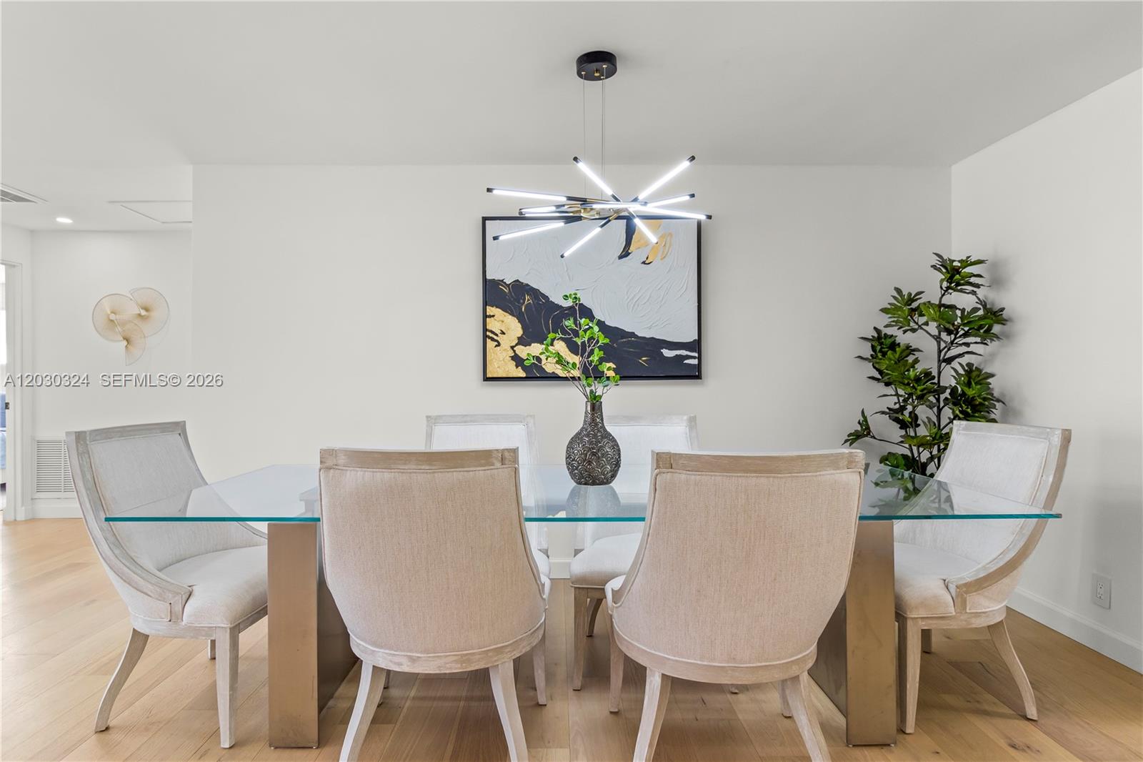A dining room features a glass-topped table, upholstered chairs, modern light fixture, and abstract art — 2862 NE 35th Ct, Lighthouse Point FL 33064, LIGHTHOUSE POINT, FL