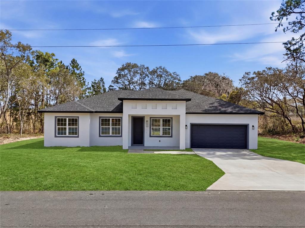 A single-story white house with a dark roof and a two-car garage — 15043 SW 60TH TERRACE, OCALA, FL