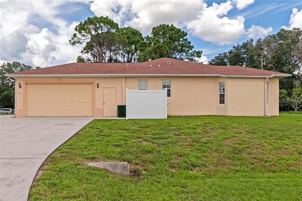 A single-story house with a peach-colored exterior, a two-car garage, and a white privacy fence — 3890 BARBARY LANE, NORTH PORT, FL