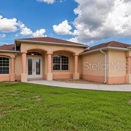 A tan single-story house with a brown roof and a front walkway under a blue sky — 3890 BARBARY LANE, NORTH PORT, FL