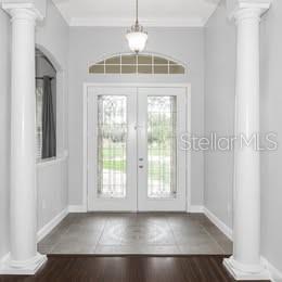 A foyer features two white columns, a tile floor, and double glass-paneled front doors — 3890 BARBARY LANE, NORTH PORT, FL