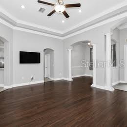 A spacious living room features dark wood flooring, light gray walls, and a tray ceiling — 3890 BARBARY LANE, NORTH PORT, FL