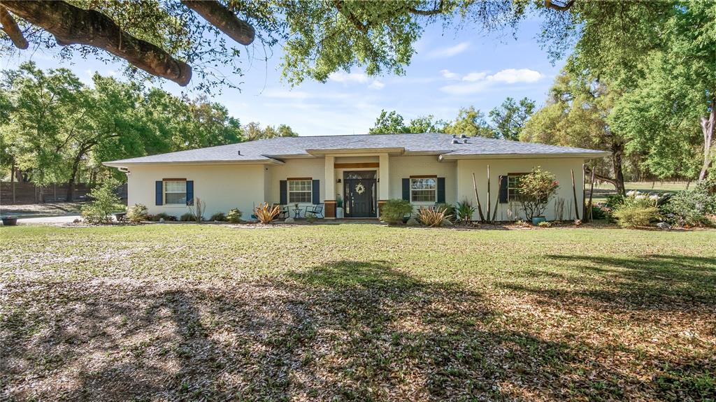 A single-story house with a light-colored exterior, dark shutters, and a large front lawn — 21289 COUNTY ROAD 455, CLERMONT, FL