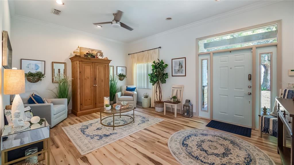 A bright living room features light wood flooring, a light blue front door, and furniture — 21289 COUNTY ROAD 455, CLERMONT, FL