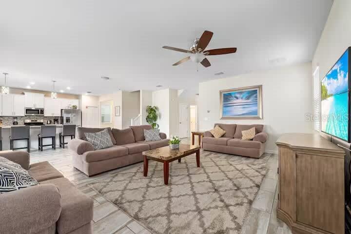 An open-concept living room features a beige sofa, a coffee table, and a kitchen island — 9045 HAZARD STREET, DAVENPORT, FL