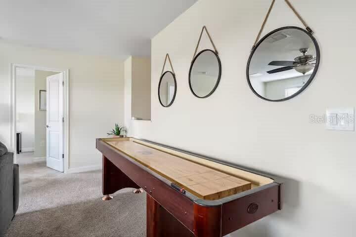 A shuffleboard table sits in a carpeted room with three hanging mirrors on the wall — 9045 HAZARD STREET, DAVENPORT, FL
