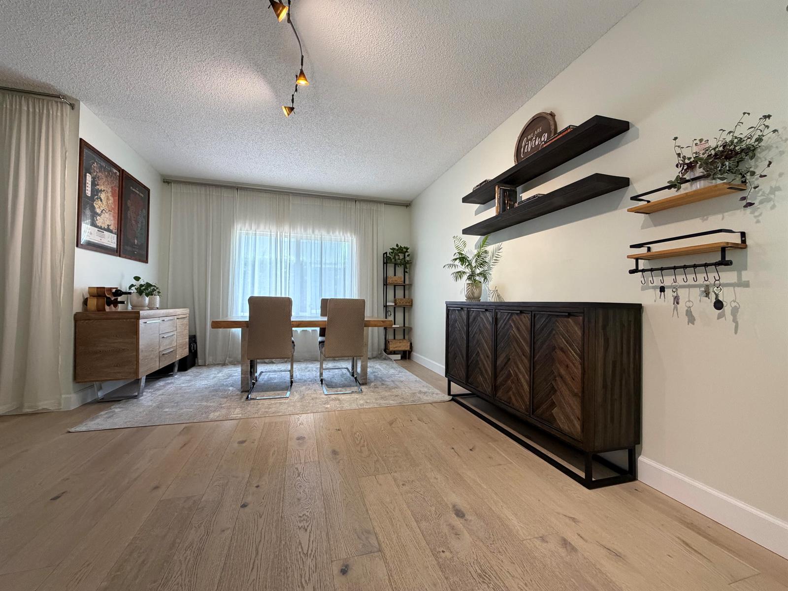 A dining room with a wooden table, chairs, sideboard, and wall-mounted shelving on light flooring — 8302 Vía Serena, Boca Raton FL 33433, BOCA RATON, FL