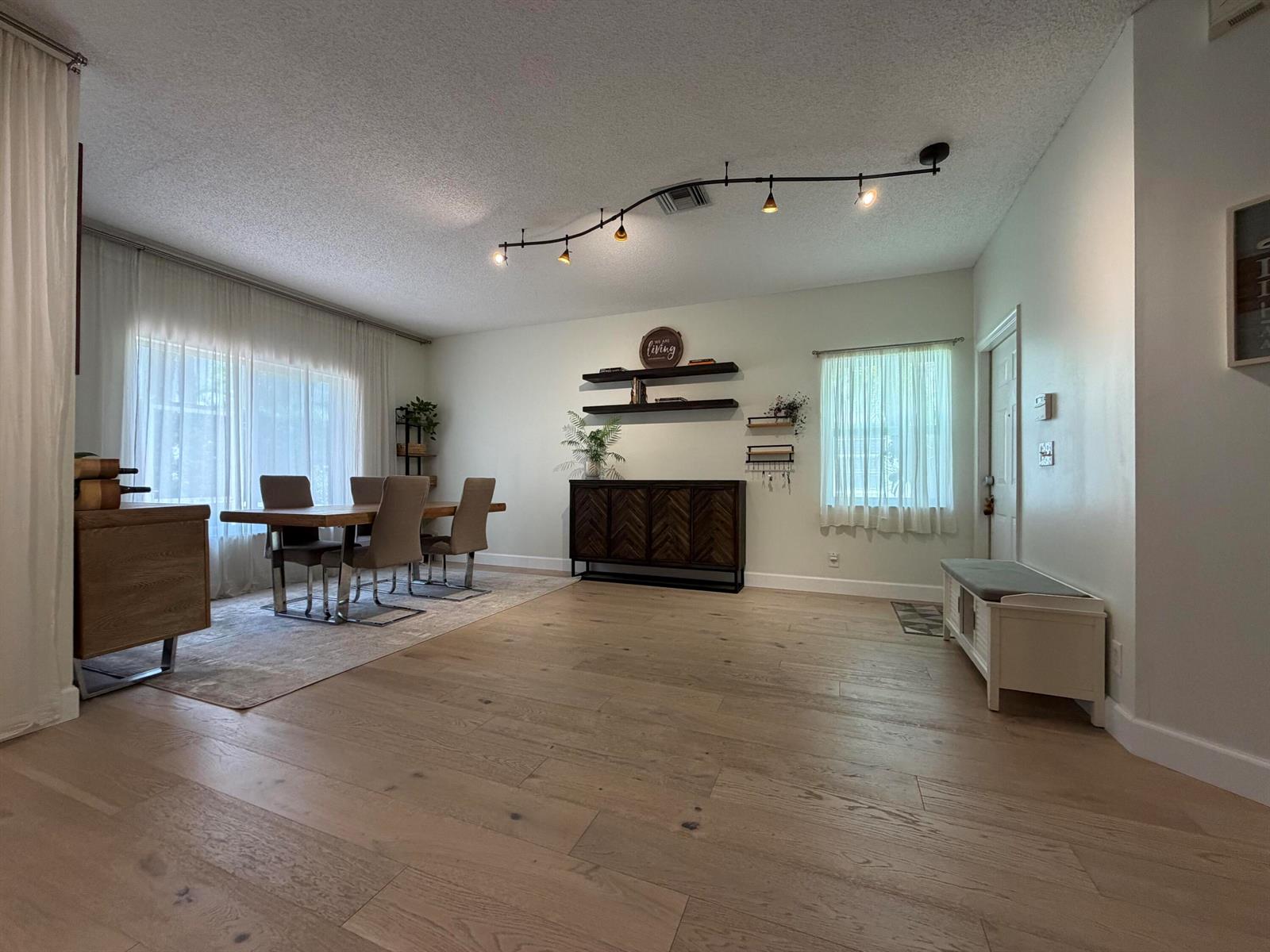 A dining area with wood flooring, a wooden table, and a dark wood sideboard — 8302 Vía Serena, Boca Raton FL 33433, BOCA RATON, FL