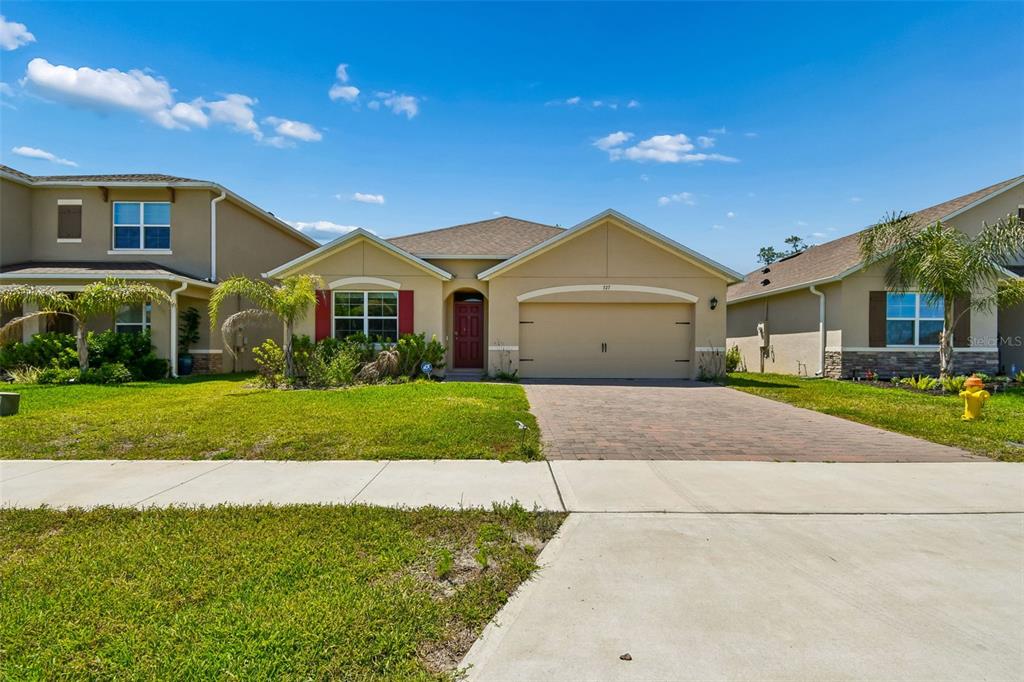 A single-story suburban house with a tan stucco exterior, a two-car garage, and a driveway — 727 LAZIO CIRCLE, DEBARY, FL