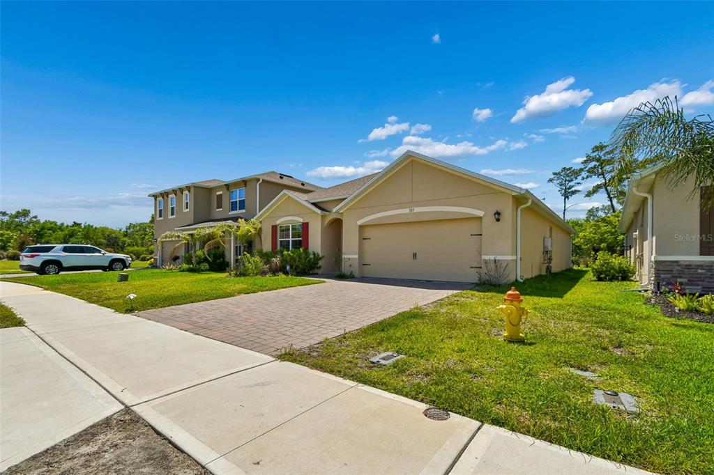 A tan single-story house with a two-car garage and a paved driveway — 727 LAZIO CIRCLE, DEBARY, FL