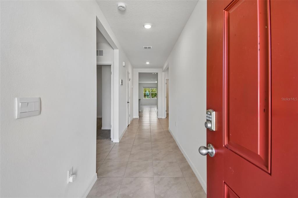 A red front door opens into a tiled hallway leading to a bright living area — 727 LAZIO CIRCLE, DEBARY, FL