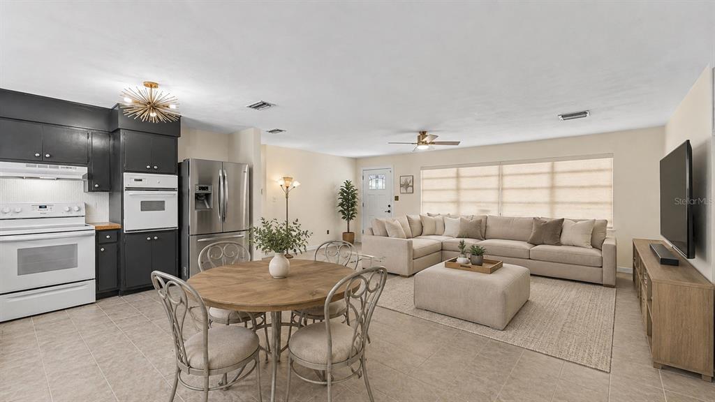 An open-concept living room and kitchen featuring a sectional sofa, dining table, and dark cabinetry — 7011 DAVIN STREET, LAKELAND, FL