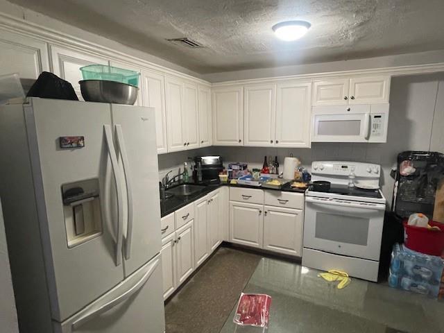A kitchen features white cabinets, black countertops, a white refrigerator, and a white stove — 2531 NE 9th Avenue, Pompano Beach FL 33064, POMPANO BEACH, FL