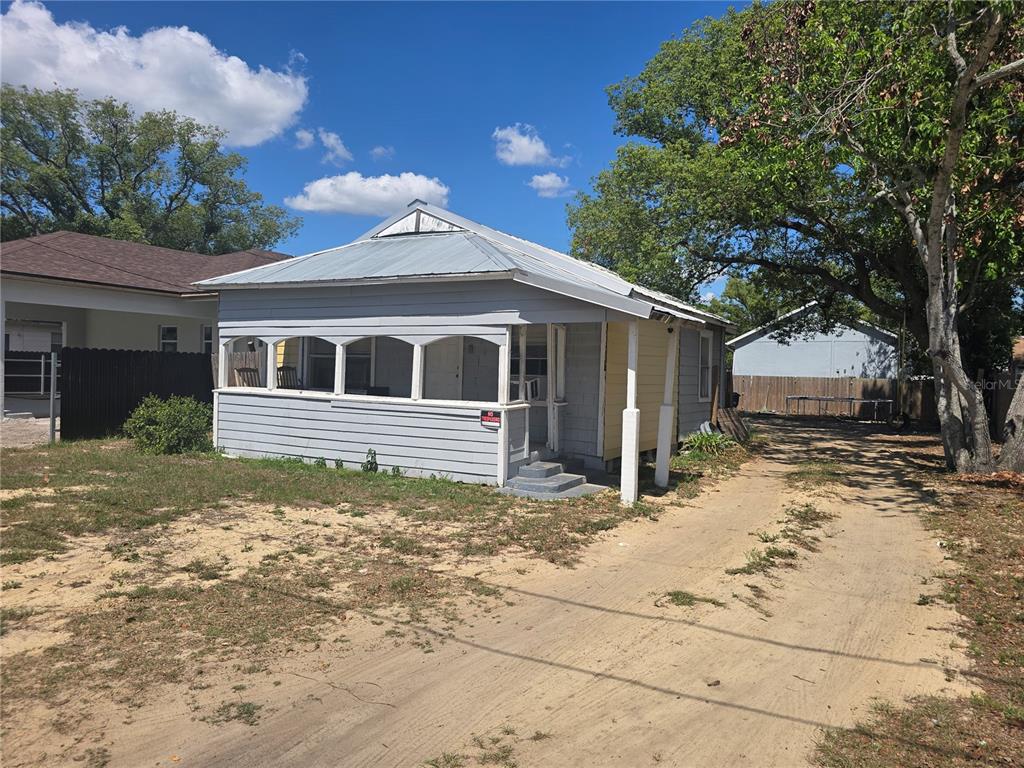 A small, light-gray, single-story house with a metal roof and a screened-in front porch — 3703 N 51ST STREET, TAMPA, FL