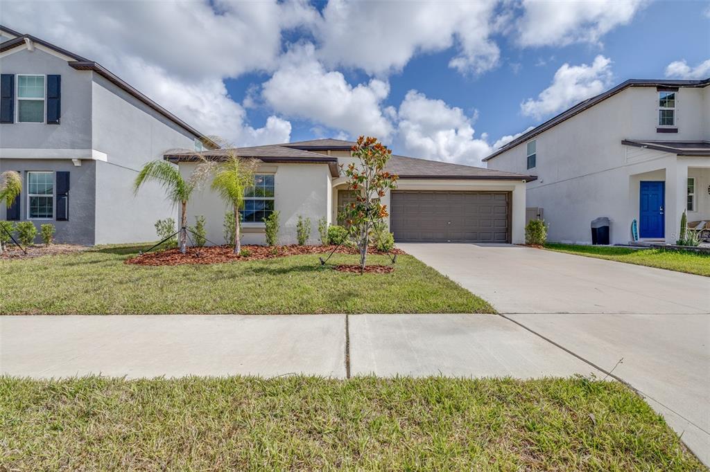 A single-story house with a two-car garage, palm trees, and a concrete driveway — 5182 FIDDLE FIG AVENUE, WIMAUMA, FL