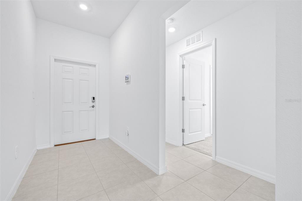 A bright entryway features white walls, light tile flooring, and a white front door — 5182 FIDDLE FIG AVENUE, WIMAUMA, FL
