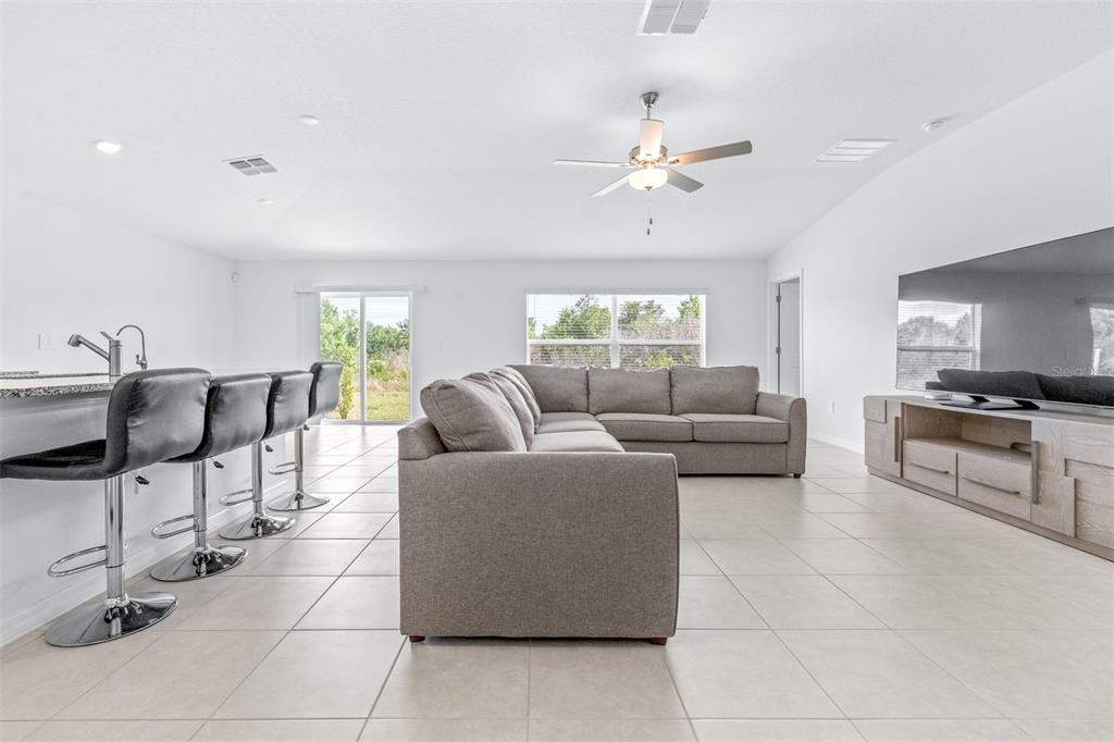 A living room features a gray sectional sofa, a television console, and a kitchen island — 5182 FIDDLE FIG AVENUE, WIMAUMA, FL