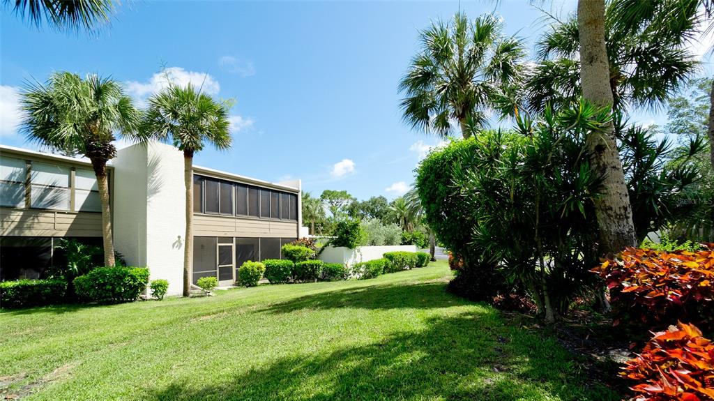 A two-story building with a screened-in porch stands on a grassy lawn with palm trees — 507 LAKESIDE DRIVE UNIT 507, BRADENTON, FL