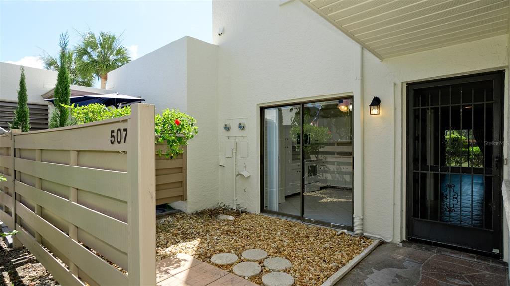 A patio area features a gravel ground, stepping stones, a sliding glass door, and a fence — 507 LAKESIDE DRIVE UNIT 507, BRADENTON, FL