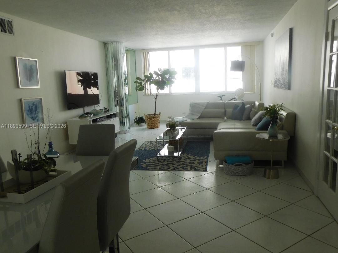 A living room and dining area feature white tile floors, a sectional sofa, and windows — 5005 Collins Ave # 322, Miami Beach FL 33140, MIAMI BEACH, FL