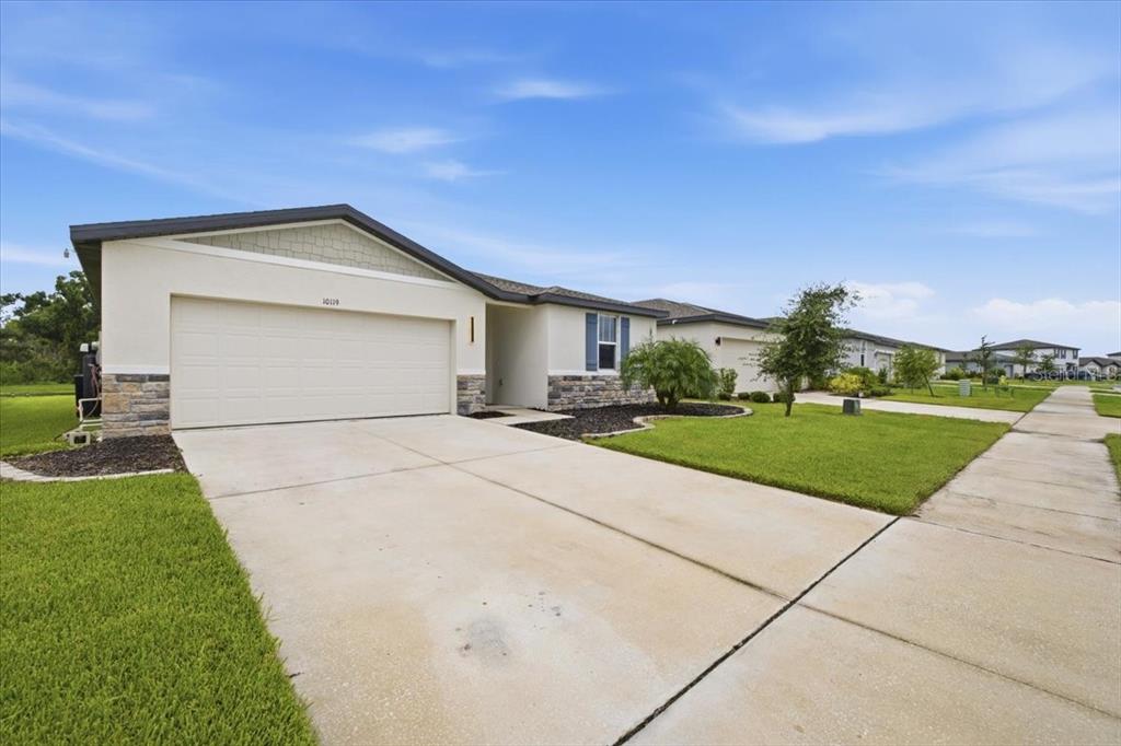 A single-story house with a two-car garage, stone accents, and a concrete driveway — 10119 DAYBREAK GLEN, PARRISH, FL