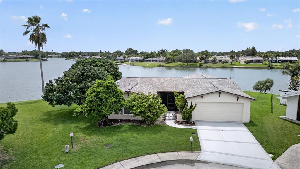 An aerial view of a single-story house with a two-car garage facing a lake — 9615 TOWANDA LANE, PORT RICHEY, FL