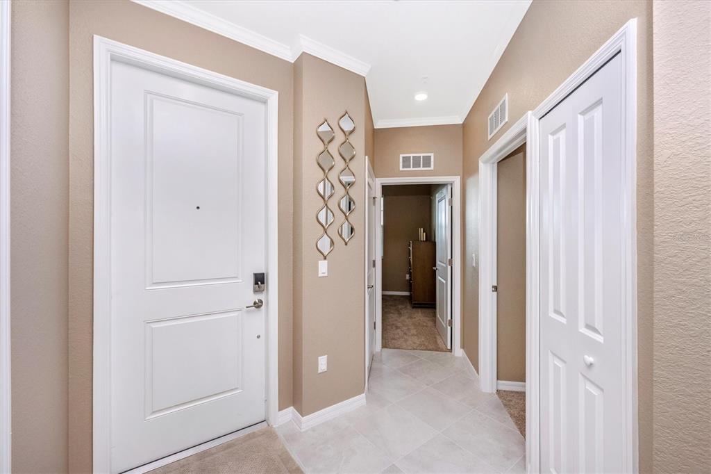 An interior entryway features a white front door, light tile flooring, and beige walls — 17625 OPAL SAND DRIVE UNIT 301, VENICE, FL
