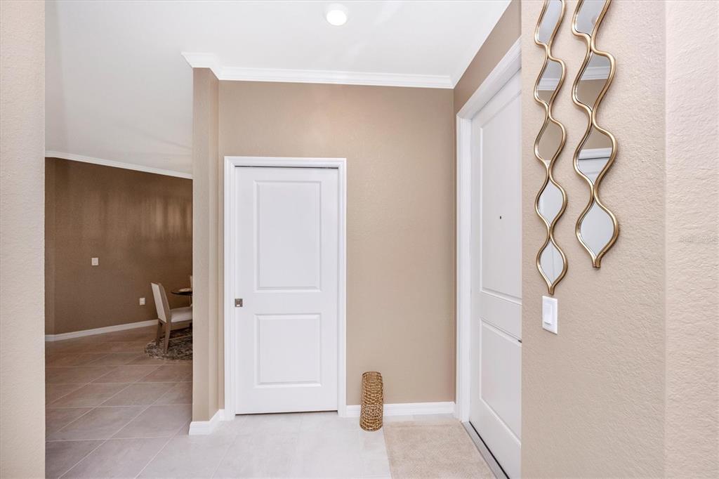 An entryway features a white door, a closet door, and a decorative gold wall mirror — 17625 OPAL SAND DRIVE UNIT 301, VENICE, FL