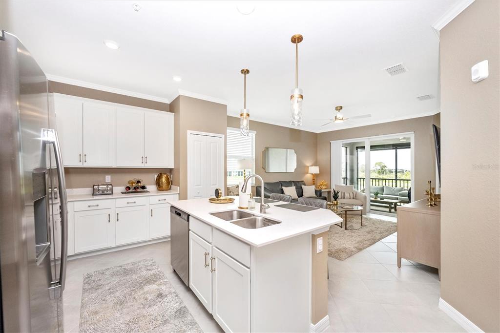 A kitchen with white cabinets and a central island overlooks an open-concept living area — 17625 OPAL SAND DRIVE UNIT 301, VENICE, FL