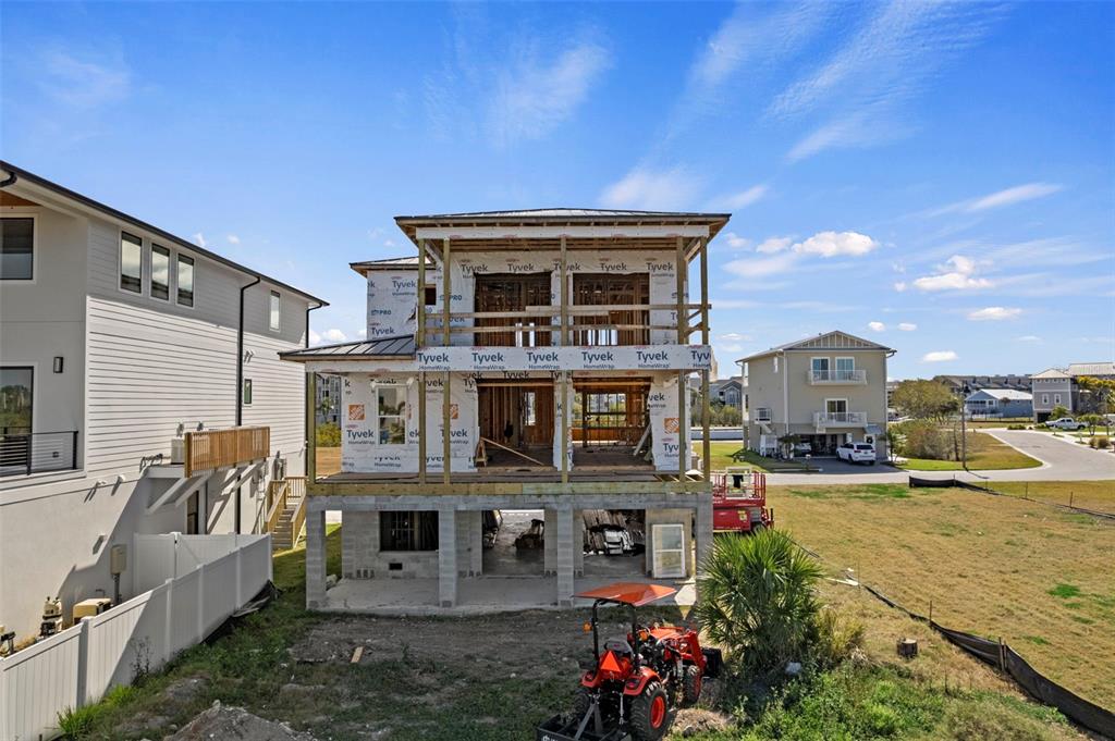 An exterior view of a multi-story house under construction with exposed framing and Tyvek wrap — 5815 ELISABETHAN LANE, NEW PORT RICHEY, FL