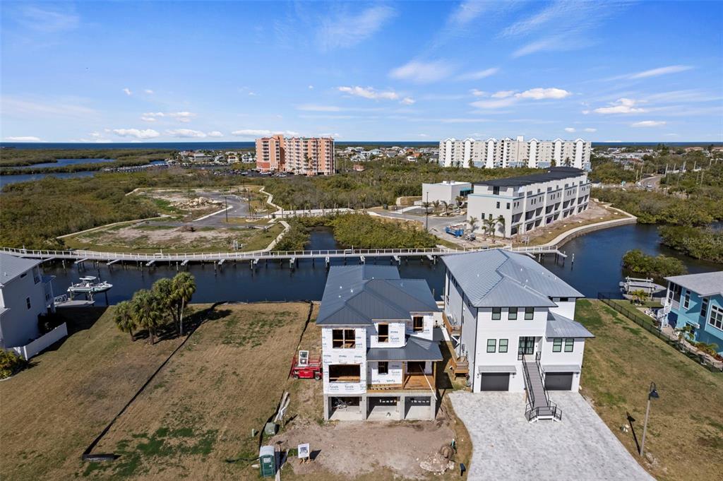 An aerial view shows two modern houses under construction near a canal and coastal landscape — 5815 ELISABETHAN LANE, NEW PORT RICHEY, FL