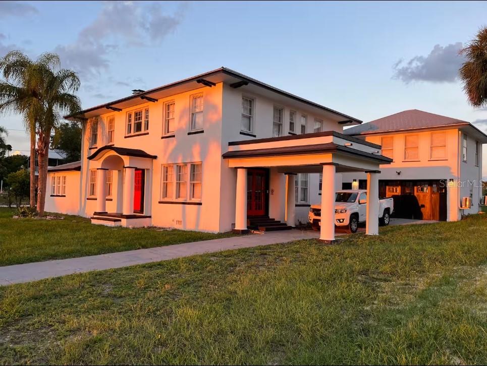 A two-story white house with a flat roof, columns, and a detached garage at sunset — 1515 LAKE EVA CIRCLE, HAINES CITY, FL