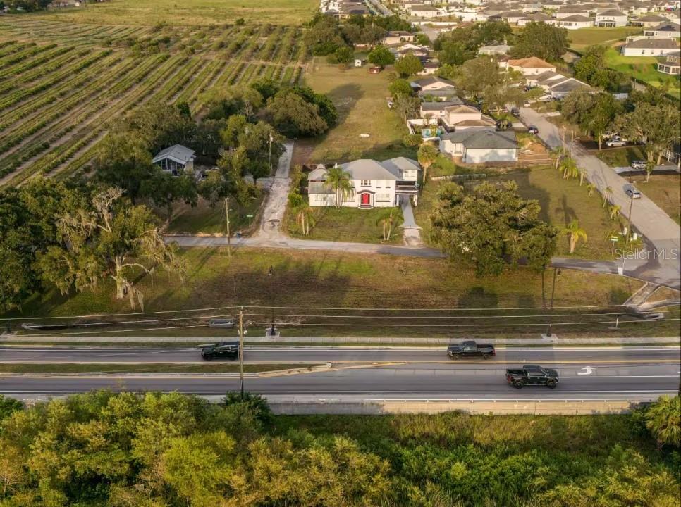 An aerial view shows a house with a red door situated near a busy road — 1515 LAKE EVA CIRCLE, HAINES CITY, FL