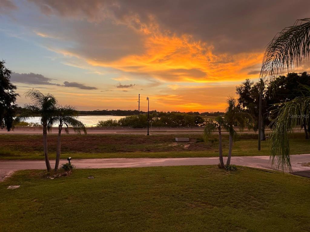 A view of a sunset over a lake with palm trees and a road — 1515 LAKE EVA CIRCLE, HAINES CITY, FL