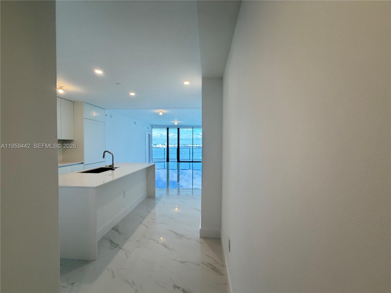 A modern kitchen with a white island and marble floors overlooks a waterfront balcony — 700 ne 24 # 3503, Miami FL 33137, MIAMI, FL